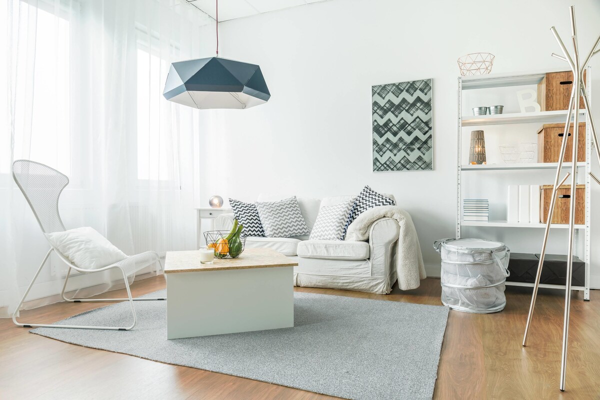 All White Living Room Interior Design With A Surface Rug And Chandelier