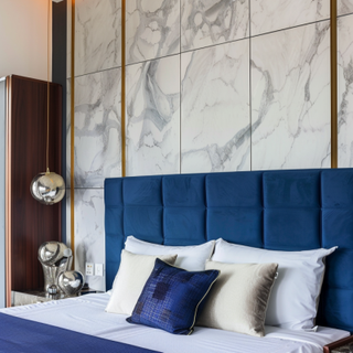 Modern Master Bedroom Design With Blue Panelled Headboard And Marble-Finish Wall Decor