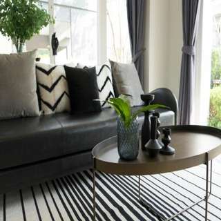 Oval Living Room Center Table Design With Patterened Rug And Leather Couch